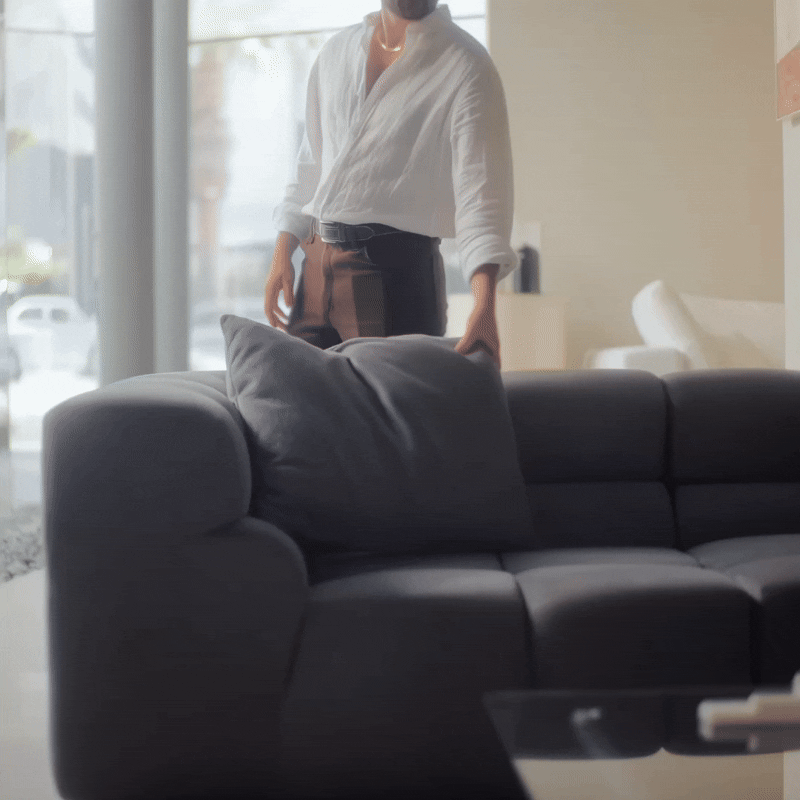 Adults playfully tossing pillows on Mario Capasa modular sofa, showcasing comfort and resilience.