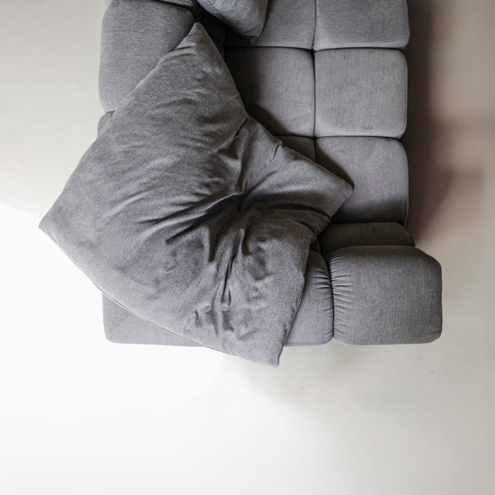 Gray sofa with a blanket draped over it on a plain background