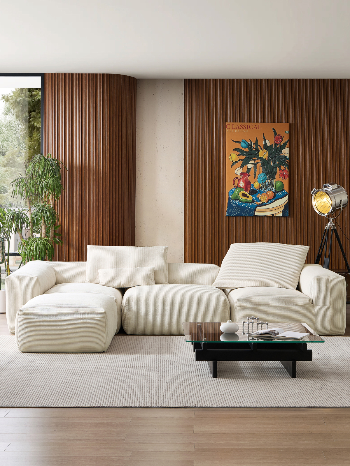 Modern living room with a white modular lounge couch by Mario Capasa. There are plants by the windows and a glass top coffee table with wood base.