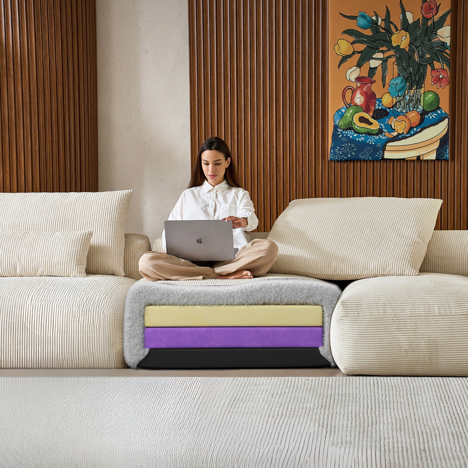 Woman using a laptop on a custom Mario Capasa sectional with a colorful painting in the background.