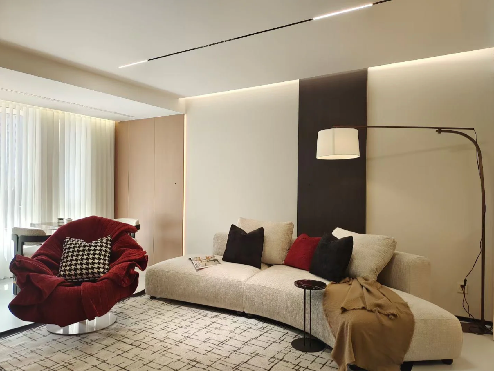 Small apartment furniture including a white sink in couch, red chair, and stylish decor elements.