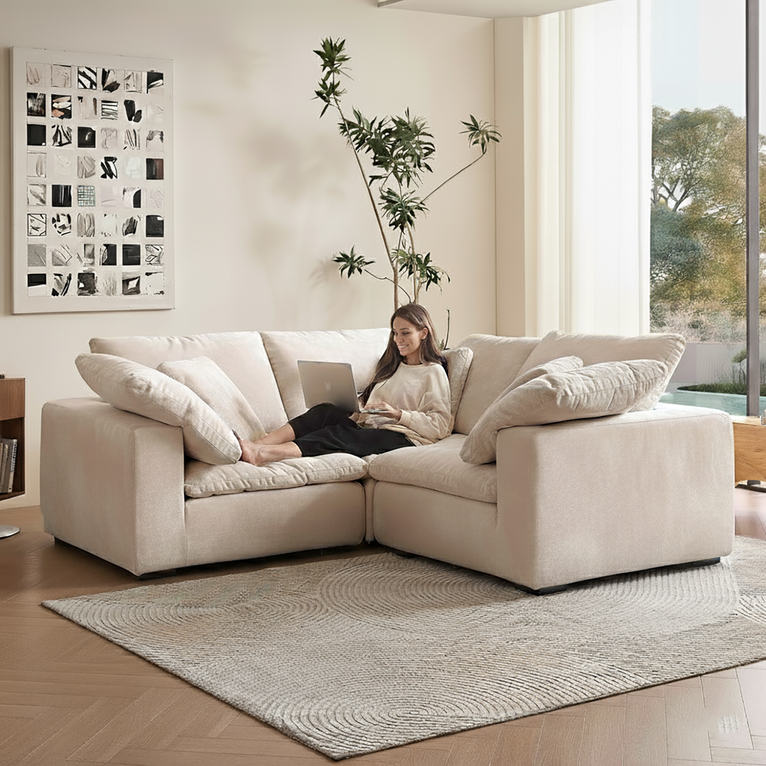 Woman using a laptop on a beige sectional sofa in a modern living room.
