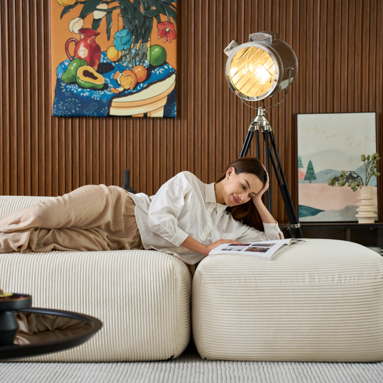 Woman reading a magazine while lying on a contemporary modular sectional by Mario Capasa in a stylish living room.