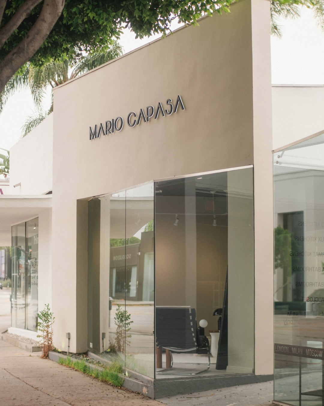 Mario Capasa store front with glass entrance and beige exterior.