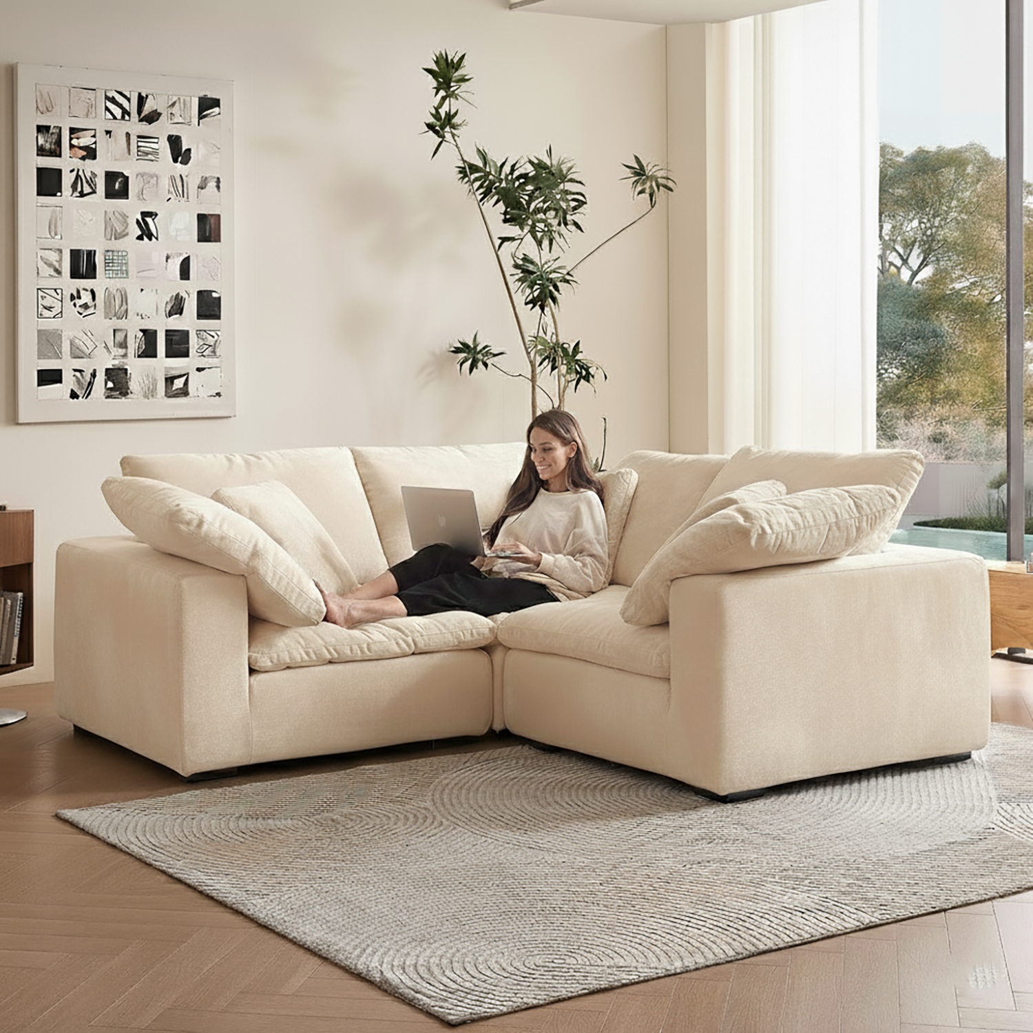 Woman using a laptop on a beige sectional sofa in a modern living room.