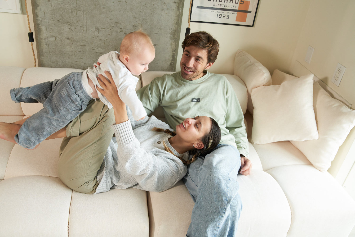 Family of three on a couch with a baby being held by the father