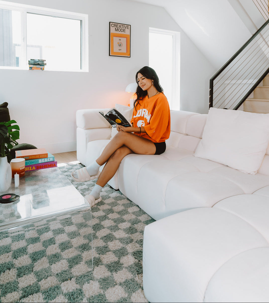 Woman sitting on a white sofa in a modern living room reading a book.